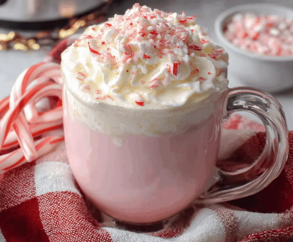 Creamy Crockpot Candy Cane White Hot Chocolate topped with whipped cream and crushed peppermint for a festive treat.
