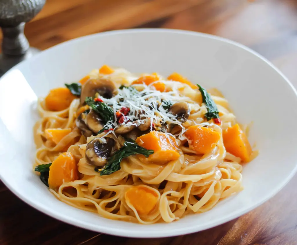 Creamy butternut squash pasta dish garnished with herbs, perfect for a cozy meal.