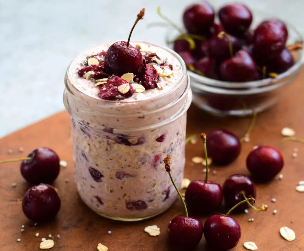 Delicious cherry overnight oats topped with fresh cherries and chia seeds in a glass jar