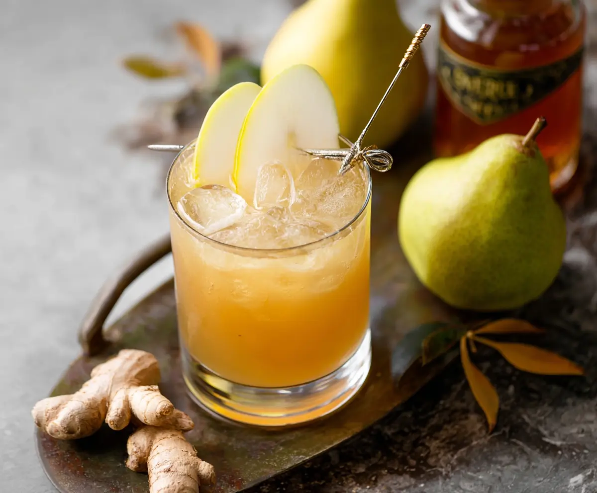 Refreshing Ginger Pear Bourbon Cocktail in a elegant glass garnished with fresh pear and ginger slices.
