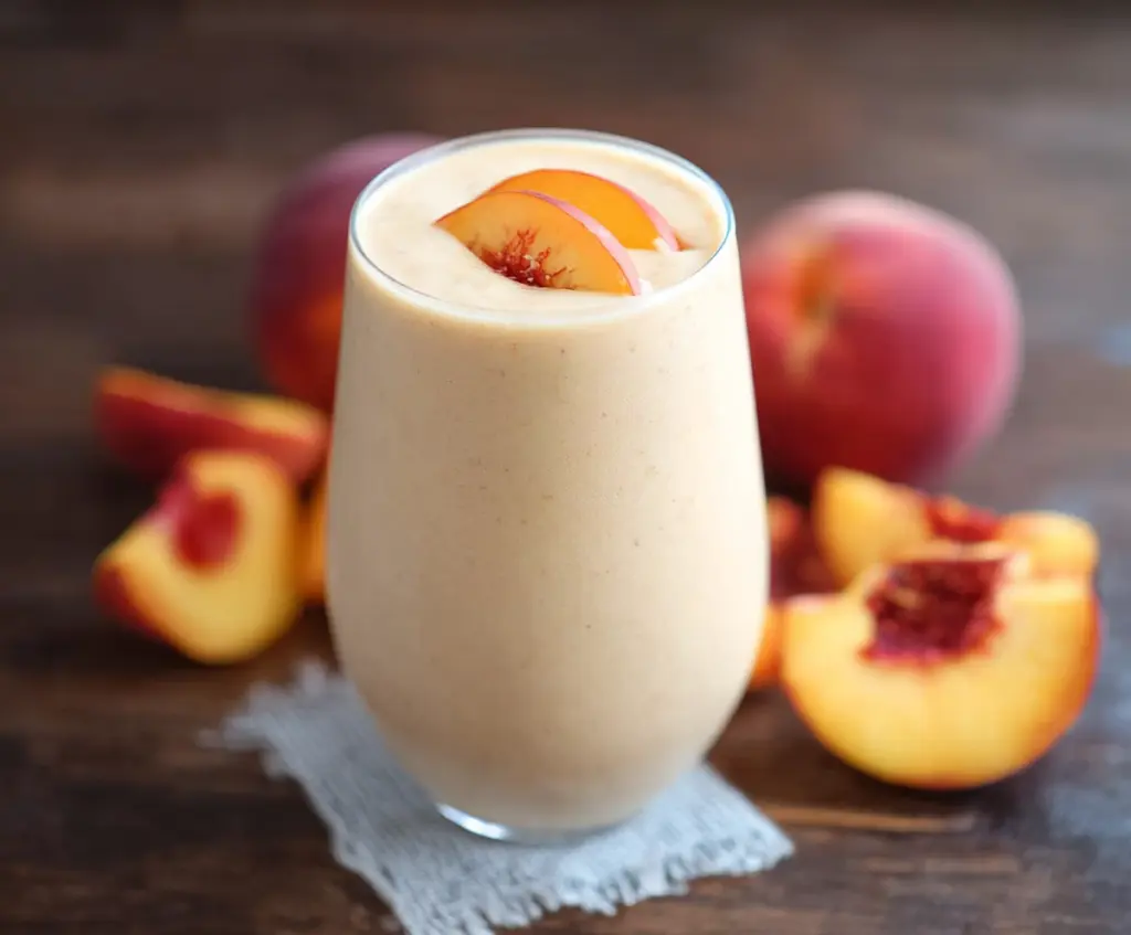 Refreshing peach protein smoothie in a glass with fresh peaches and yogurt, perfect for a nutritious breakfast.