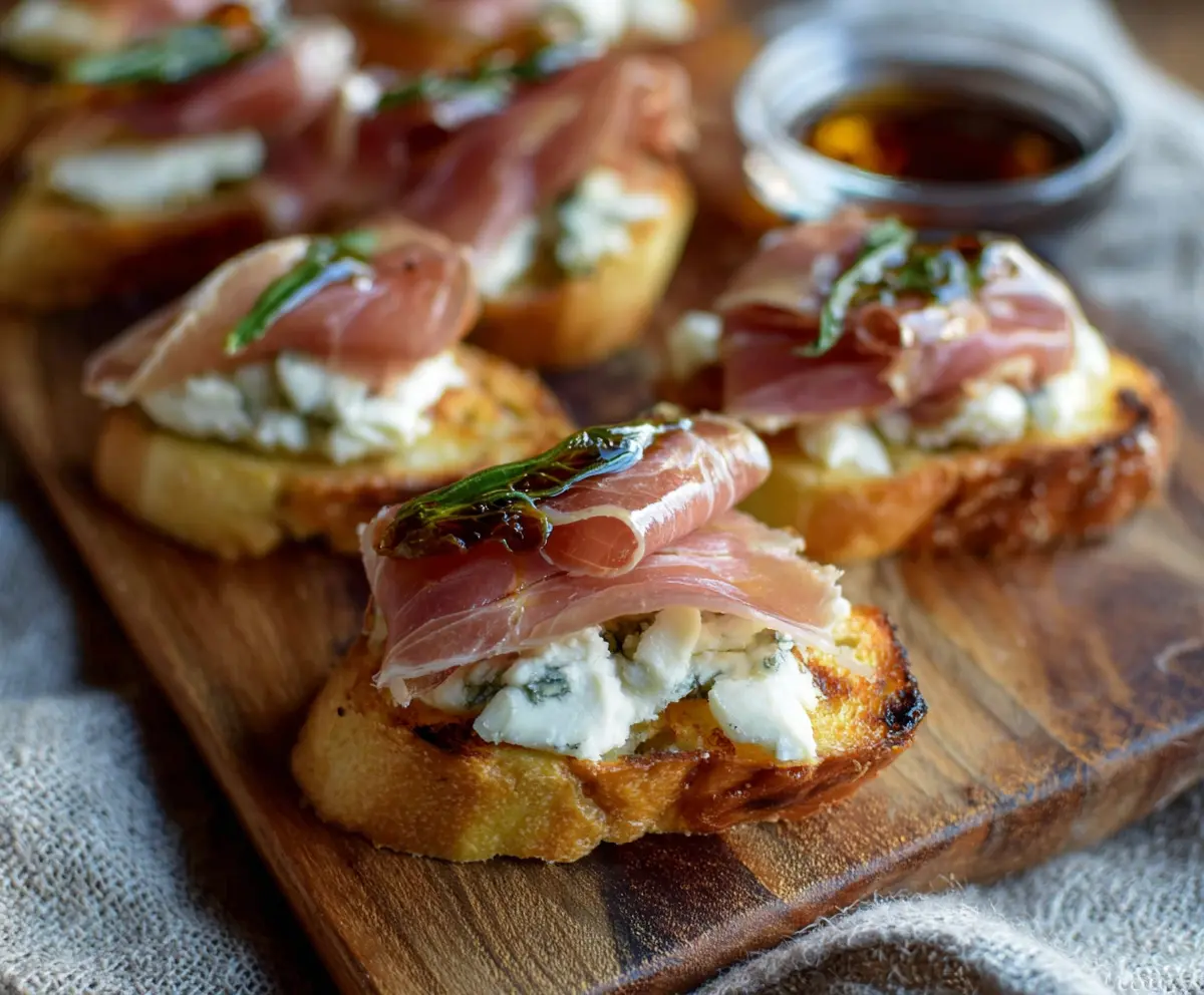 Delicious Prosciutto Pear Gorgonzola Crostini served on a rustic platter with fresh ingredients.