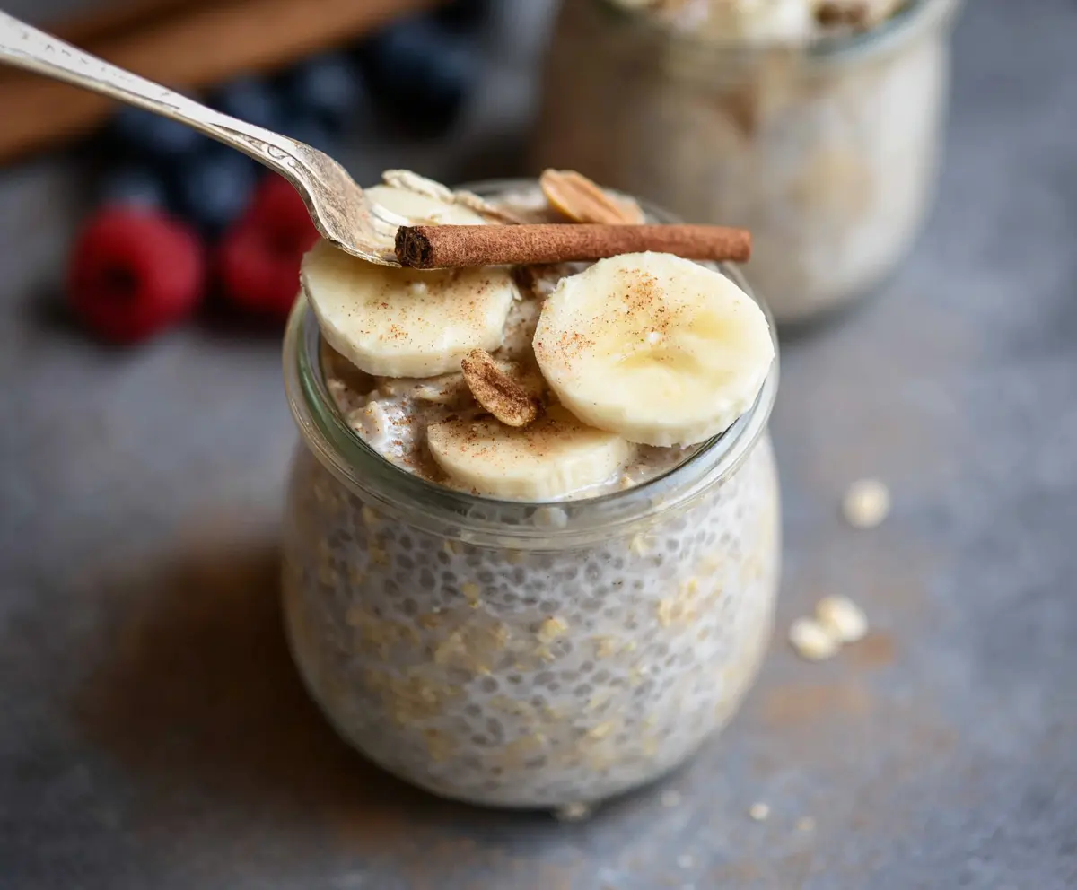Creamy cinnamon vanilla overnight oats in a glass jar topped with fresh berries and a sprinkle of cinnamon.