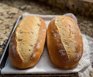 Golden crust sourdough discard French bread loaf on a wooden cutting board.