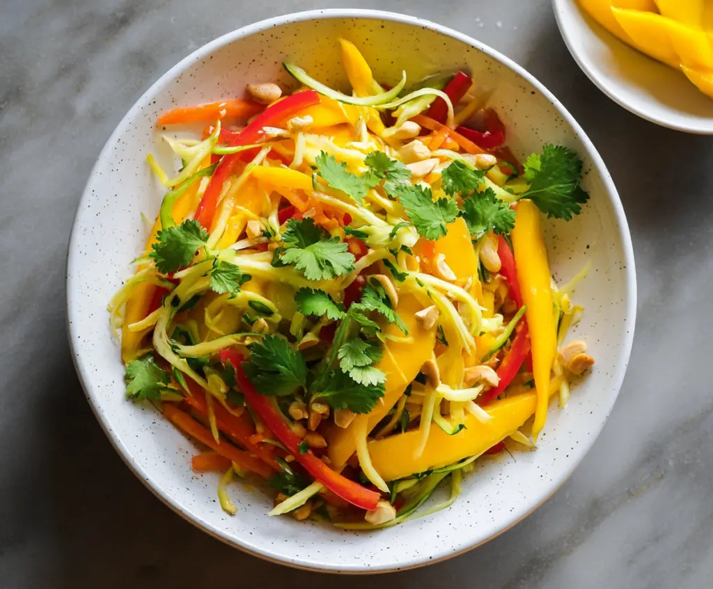 Fresh Thai Mango Salad with herbs, chili, and lime served in a bowl