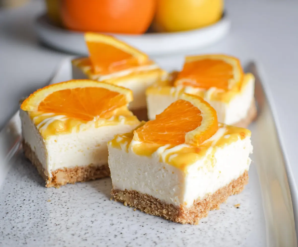 Delicious Orange Creamsicle Cheesecake Bars with a creamy orange-flavored topping and graham cracker crust.